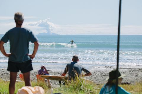 Spectators watching the surfing with Whakaari in the background